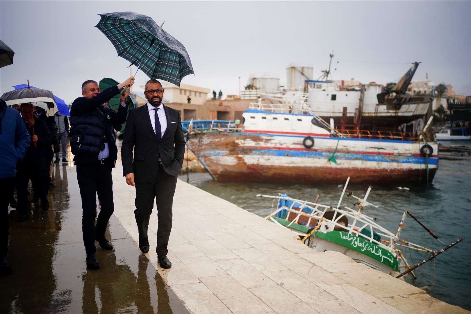 Home Secretary James Cleverly walks past a sunken boat used by migrants to cross from Africa during a visit to Lampedusa Port (Victoria Jones/PA)