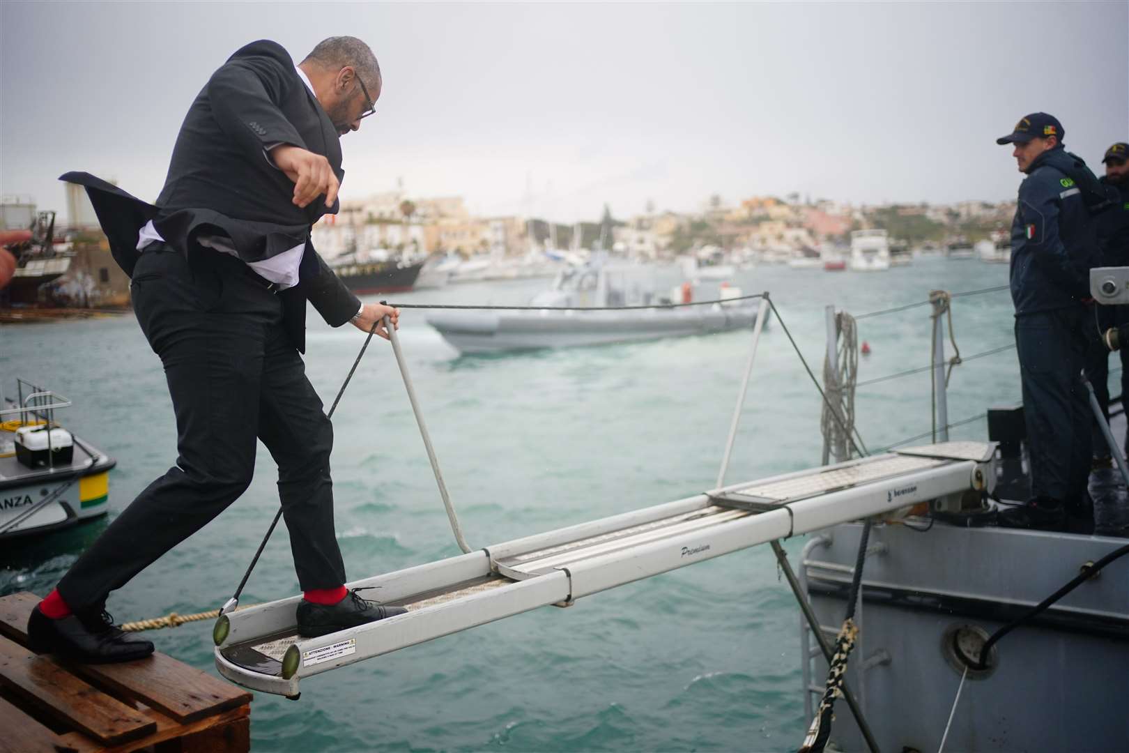 Mr Cleverly climbs on to a Guardia di Finanza police boat in Lampedusa Port (Victoria Jones/PA)